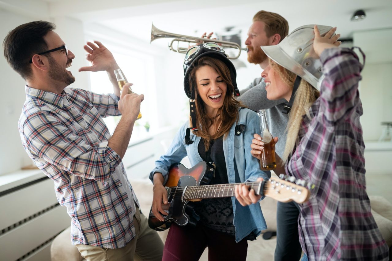 Friends having fun and partying in house and playing music